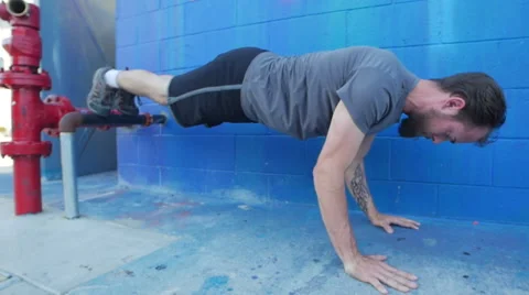 A young man with a beard doing push-ups in the street, slow motion. Stock Footage 68537077