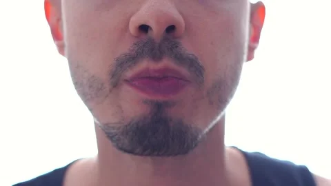 Young man with beard is eating, biting and chewing a green apple close up. Video stock 220559887