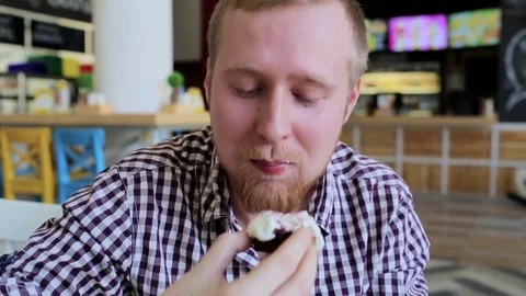 A young man with a beard is eating cake Stock-Footage 74488316