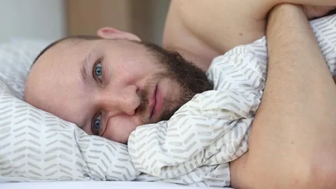 Young man with a beard falls asleep in bed Video stock 242720273
