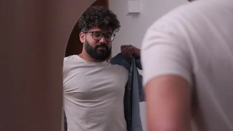 Young man with beard getting dressed in front of mirror Video stock 346989606