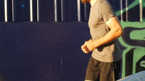 A young man with a beard going for a run in an urban environment. 動画素材 67981428