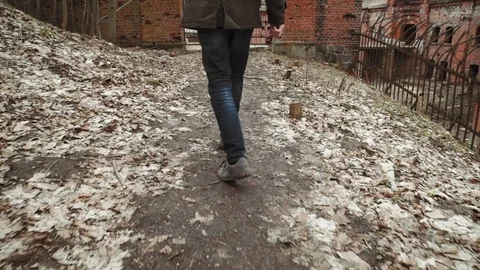 A young man With a beard, in a gray coat walks through the park in the spring or Stock Footage 74127611