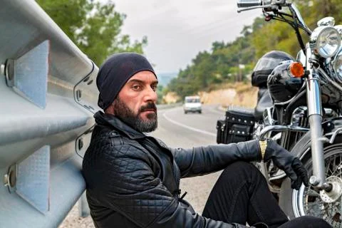 Young Man with beard having rest in the countryside during motorbike trip. Stock Photos