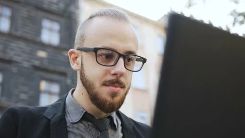 A young man with a beard in his glasses works a computer Stock Footage 79279911