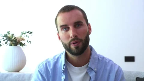 Young man with a beard looking at the camera, smiling, waving, and talking Stock Footage 344782193
