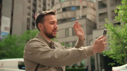 Young man with beard make video call using smartphone on the city background.Guy Stock Footage 247297302
