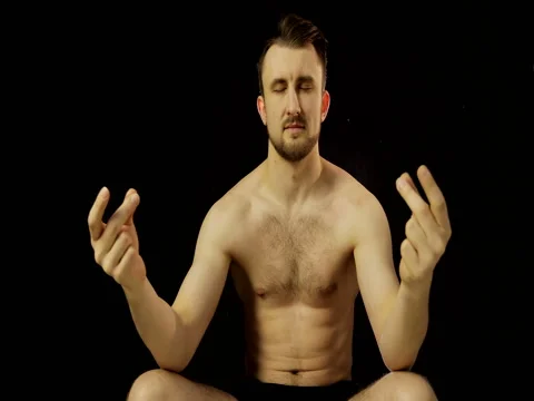 A young man with a beard, meditating on a black background. Stock Footage 73076455