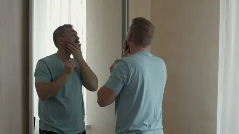 Young man with a beard at the mirror Video stock 155796387