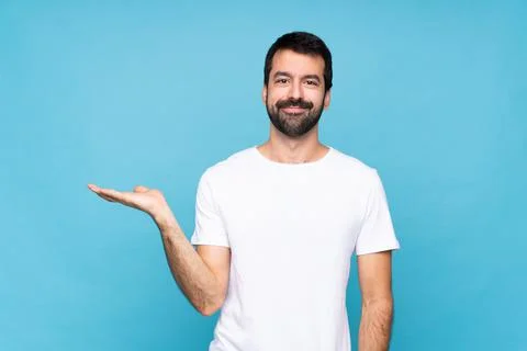 Young man with beard  over isolated blue background holding copyspace imagina Stock Photos