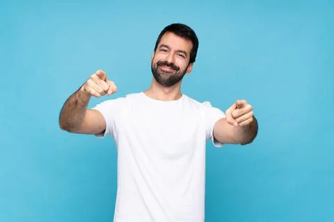 Young man with beard  over isolated blue background points finger at you whil Stock Photos