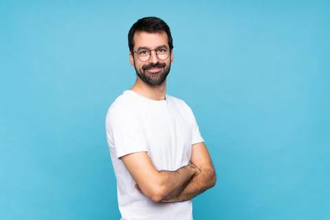 Young man with beard  over isolated blue background with glasses and smiling Foto stock