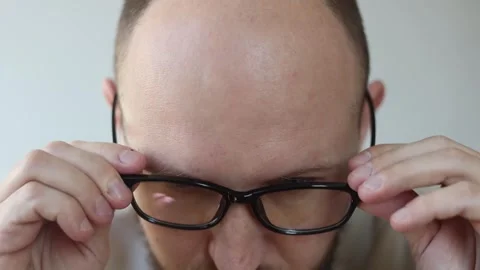 Young man with a beard puts on glasses smiling Stock Footage 242720348