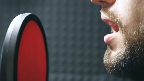 Young man with beard recording new song. Male singer in headphones singing song Stock Footage 306255075