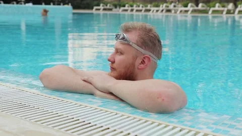 Young man with beard rest in the pool with swimming goggles by the hotel Video stock 147039038