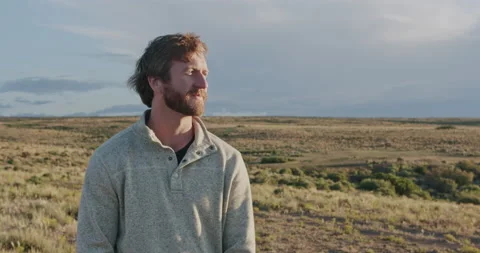 Young man with a beard smiling and looking around at the Colorado sunset Stock Footage 167336435