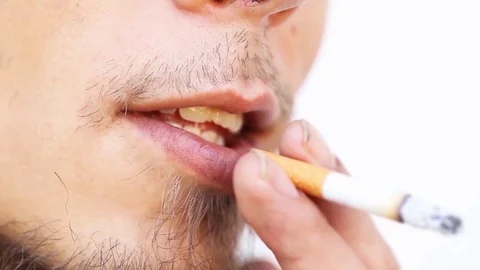 Young man with beard is smoking a cigarette on a white background Stock Footage 101066847