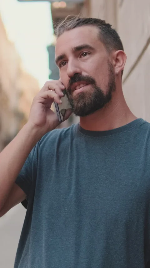 Young man with beard is talking on cellphone on the background of the old city Stock Footage 226919903
