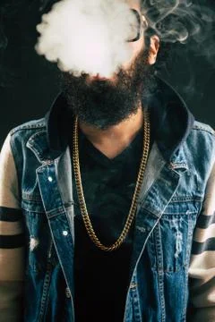 Young man with beard throwing a cloud of steam. Black background. Vaping an Stock Photos