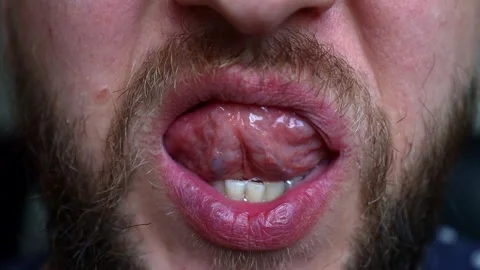 A young man with a beard tries the cleanliness of his teeth with his tongue Video stock 242720080