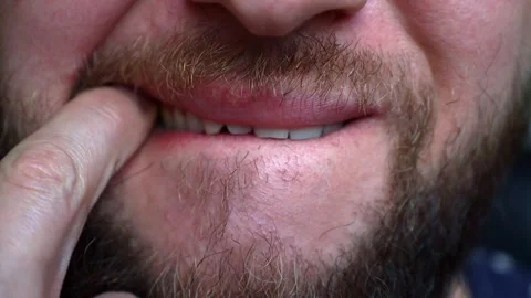 A young man with a beard tries something stuck in his tooth Stock Footage 242720134