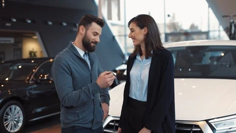 Young man with beard turning keys of new car in hands. Guy kidding and girl Stock Footage 86174753