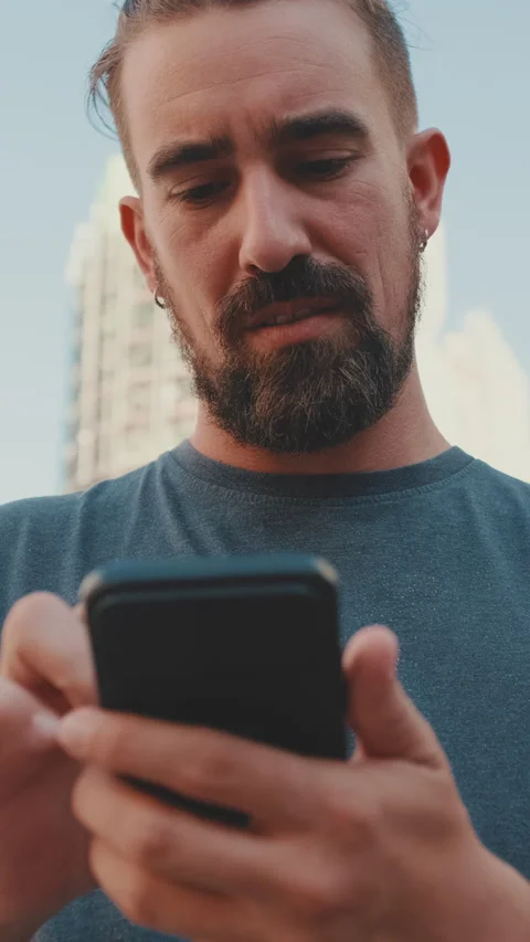Young man with beard uses map application on mobile phone Vídeo Stock 226920701