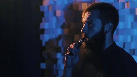 Young man with beard vaping an electronic cigarette. Vaper hipster smoke Stock Footage 80985155
