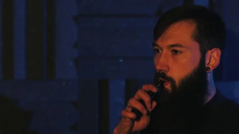 Young man with beard vaping an electronic cigarette. Vaper hipster smoke Stock Footage 80985436