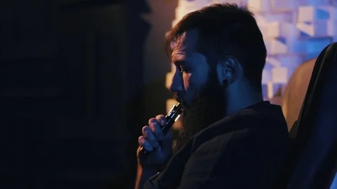 Young man with beard vaping an electronic cigarette. Vaper hipster smoke Stock Footage 80985584