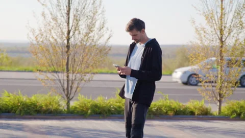 Young man with beard walks and looks at his mobile phone. Confident man uses a Stock Footage 314308410