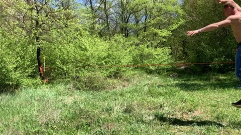 A young man with a beautiful torso is walking along a slackline. Stock Footage 108105758
