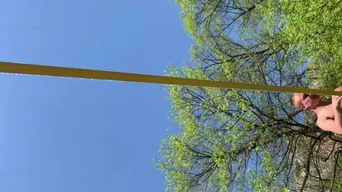 A young man with a beautiful torso is walking along a slackline. Stock Footage 108105925
