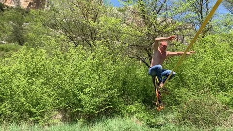 A young man with a beautiful torso is walking along a slackline. Stock Footage 108106446