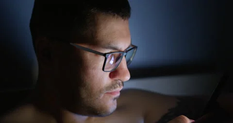 Young man in bed looks at the screen of his smartphone. Stock-Footage 154324724