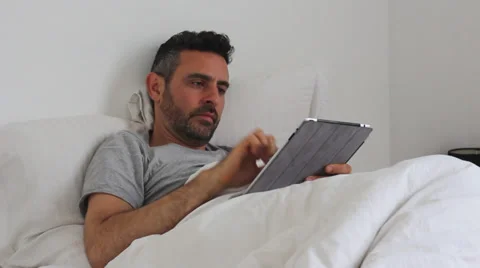 A young man in bed with smartphone and tablet Stock Footage 35755860