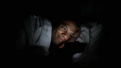Young man in bed using his phone in the dark Stock Footage 99390541