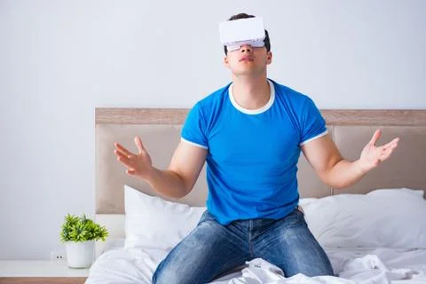 Young man in bed wearing a vr virtual reality head set Stock Photos