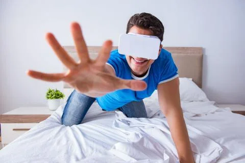 Young man in bed wearing a vr virtual reality head set Stock Photos