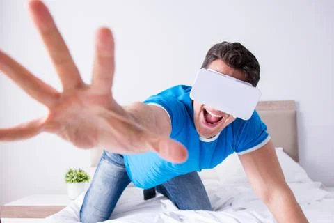 Young man in bed wearing a vr virtual reality head set Stock Photos