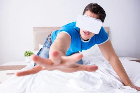 Young man in bed wearing a vr virtual reality head set Stock Photos