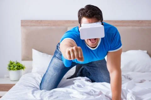 Young man in bed wearing a vr virtual reality head set Stock Photos