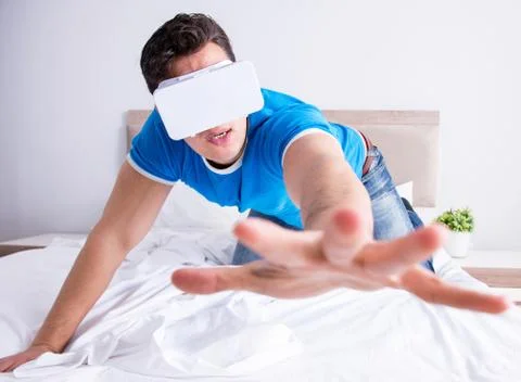 Young man in bed wearing a vr virtual reality head set Stock Photos
