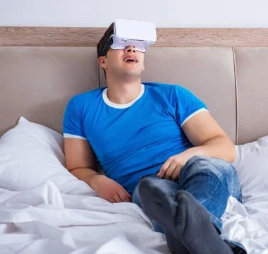 Young man in bed wearing a vr virtual reality head set Stock Photos