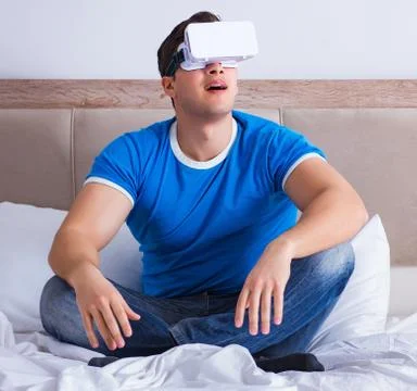 Young man in bed wearing a vr virtual reality head set Stock Photos