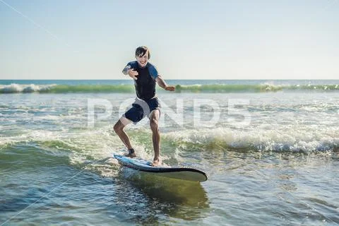 Young man, beginner Surfer learns to surf on a sea foam on the Bali island Stock Photos