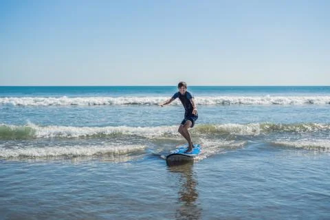 Young man, beginner Surfer learns to surf on a sea foam on the Bali island Stock Photos