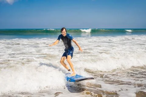 Young man, beginner Surfer learns to surf on a sea foam on the Bali island Stock Photos