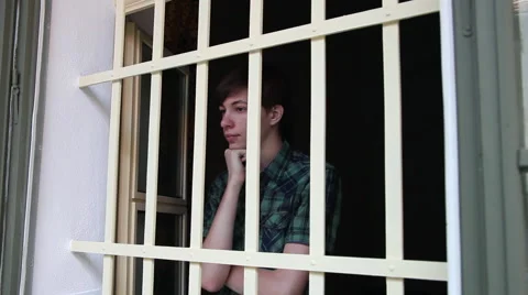 Young man behind the bars, depressed, teenage boy, orphanage, orphan Stock Footage 44890971