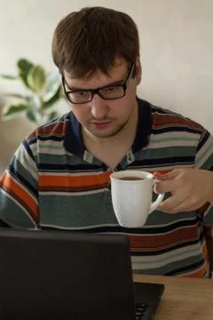 Young Man Behind a Laptop Drinking Tea Foto stock